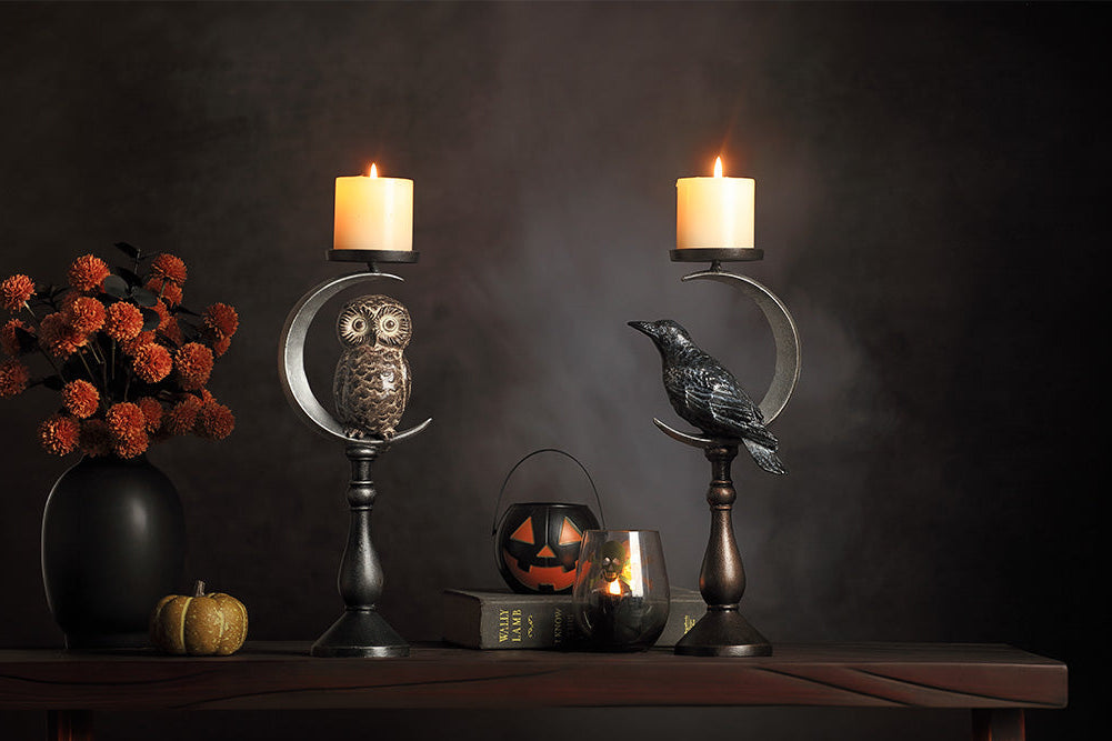 Halloween-themed candle holders with candles, pumpkins, and flowers on a dark background.