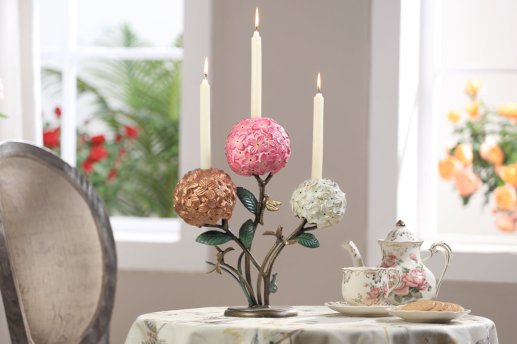 A candleholder featuring 3 hydrangea blossoms with dragonflies and a snail.