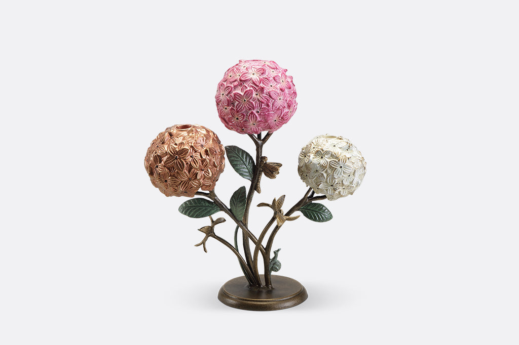 A candleholder featuring 3 hydrangea blossoms with dragonflies and a snail.