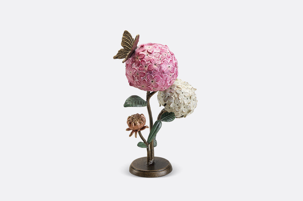 A single taper candle candle holder with two blooming hydrangeas, a butterfly, and a snail.