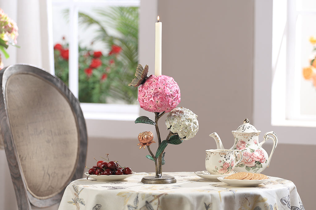 A single taper candle candle holder with two blooming hydrangeas, a butterfly, and a snail.