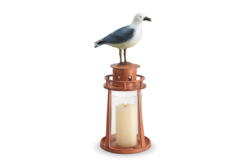 Candle holder with a seagull figurine on top against a white background