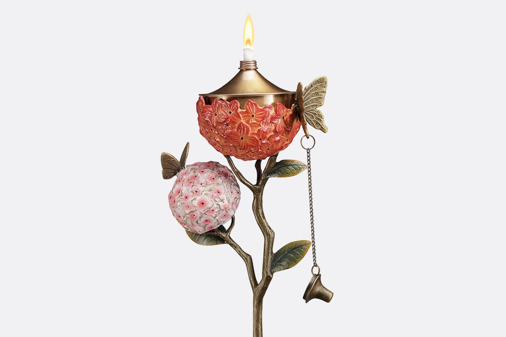 Decorative garden stake holding a candle with floral design on a white background