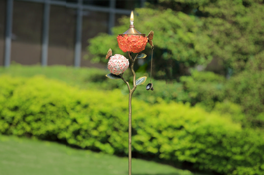 Decorative garden stake holding a candle with floral design with greenery background