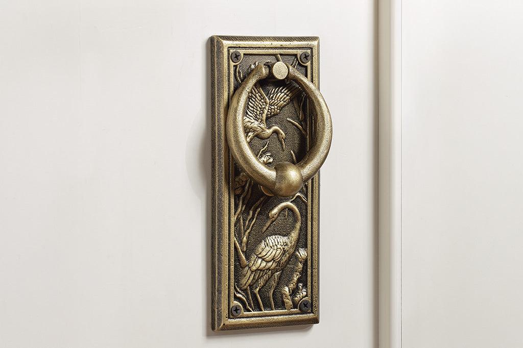 A doorknocker with embossed cranes and wildlife.