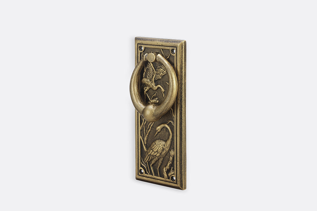 A doorknocker with embossed cranes and wildlife.