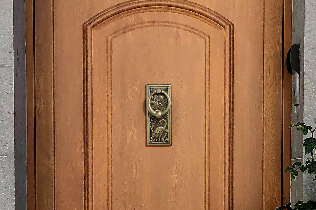 A doorknocker with embossed cranes and wildlife.