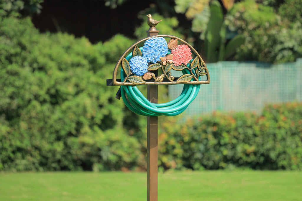 Decorative garden hose holder with floral design in a garden setting