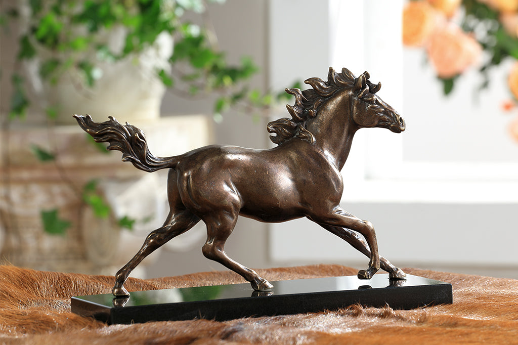 Brass sculpture of a horse running on a marble base.