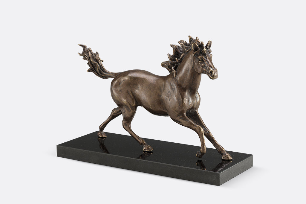 Brass sculpture of a horse running on a marble base.
