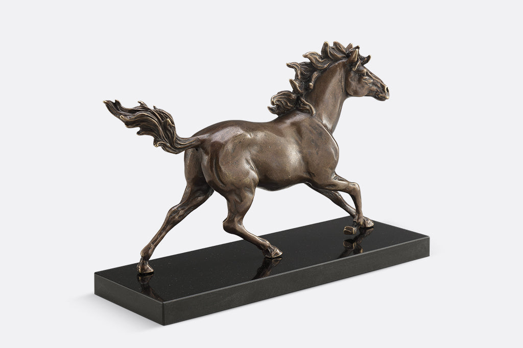 Brass sculpture of a horse running on a marble base.