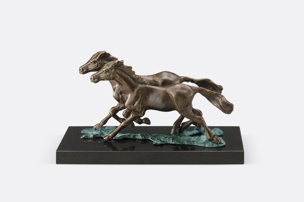 Brass sculpture of two horses running on water on a marble base.