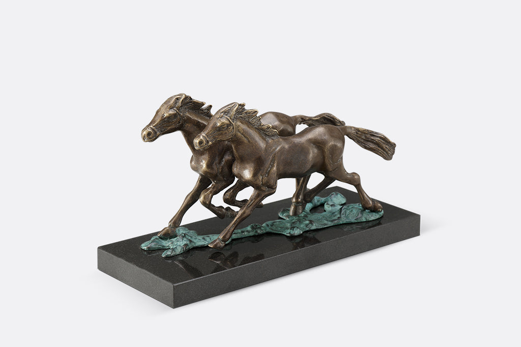Brass sculpture of two horses running on water on a marble base.