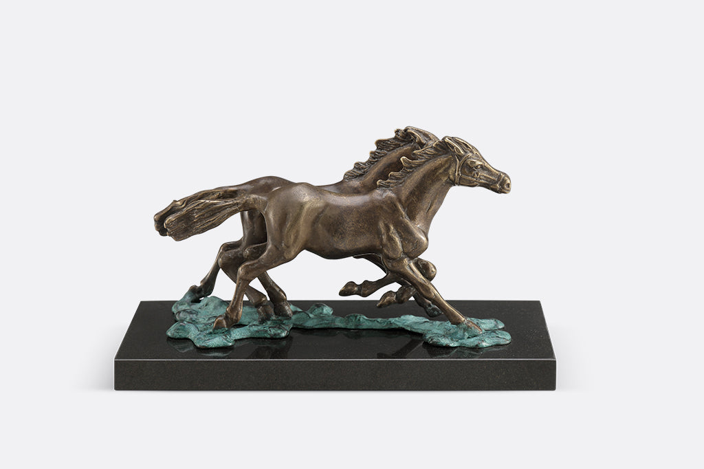 Brass sculpture of two horses running on water on a marble base.
