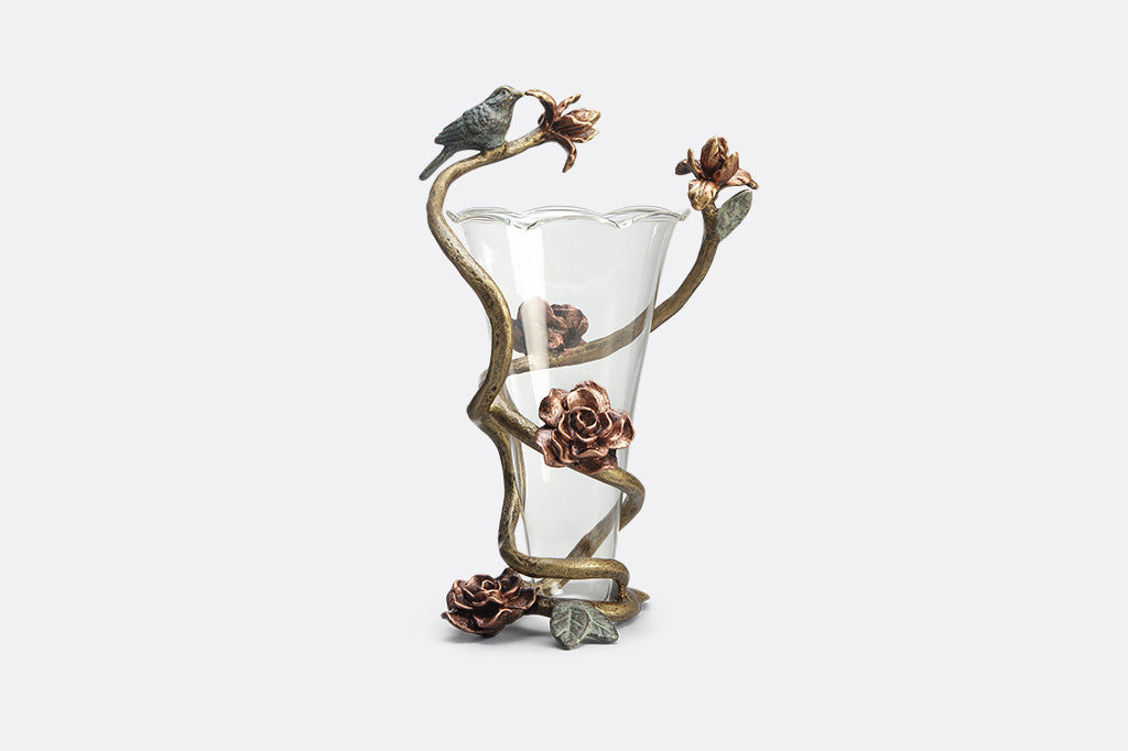 Rose inside glass vase with aluminum flower like detail surrounding vase with small bird sculpture attached