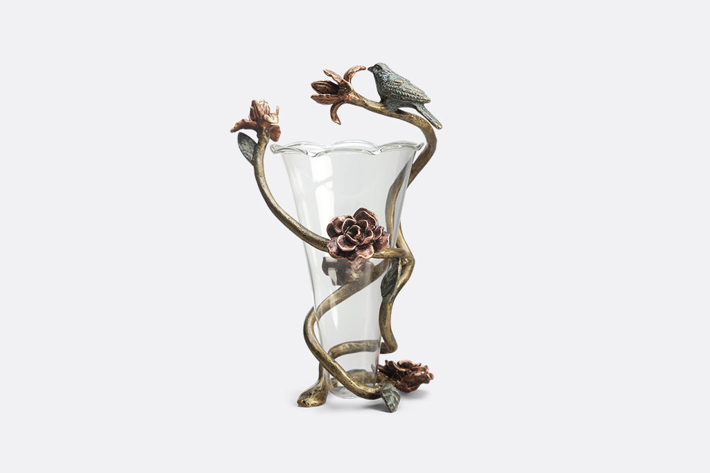 Rose inside glass vase with aluminum flower like detail surrounding vase with small bird sculpture attached