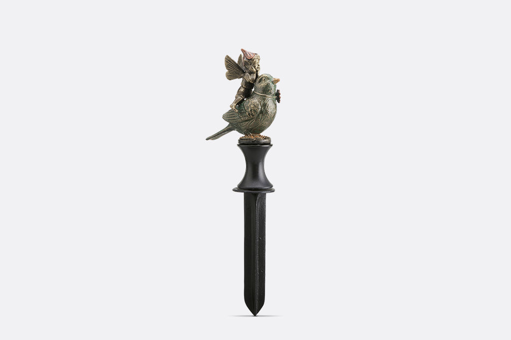 Decorative garden stake with bird and fairy figurines on a white background