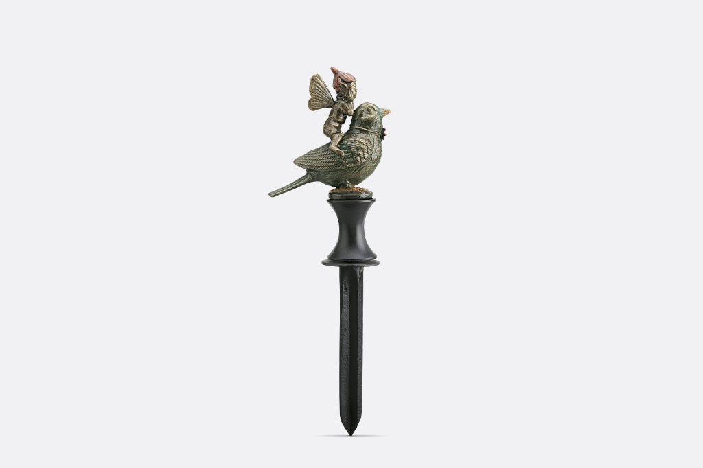 Decorative garden stake with bird and fairy figurines on a white background