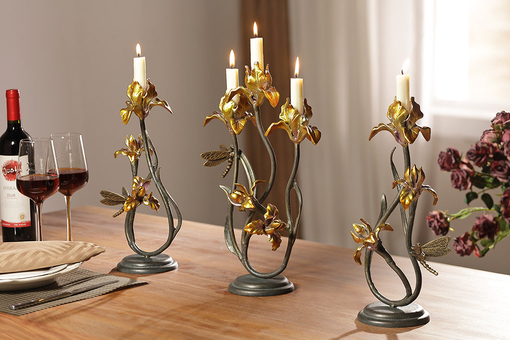 A taper candleholder shaped like Iris flowers with a dragonfly with a pair of Iris shaped candleholders.