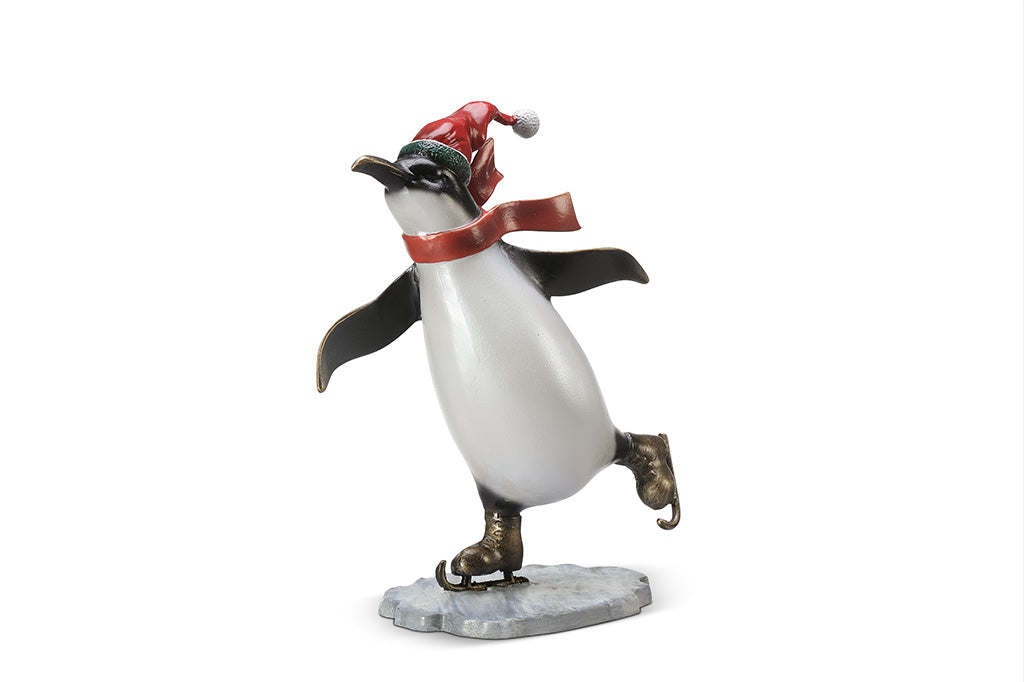 A sculpture of a penguin wearing a scarf and Santa hat ice skating.