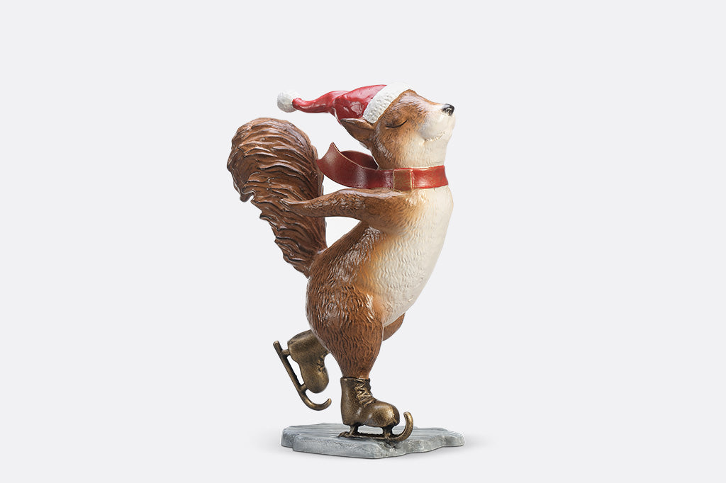 A statue of a squirrel wearing a santa hat and scarf ice skating.