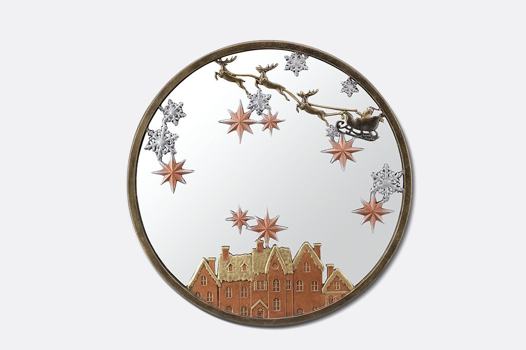 A round mirror with details of Santa and his sleigh being pulled by reindeer across a sky of stars and over rooftops.
