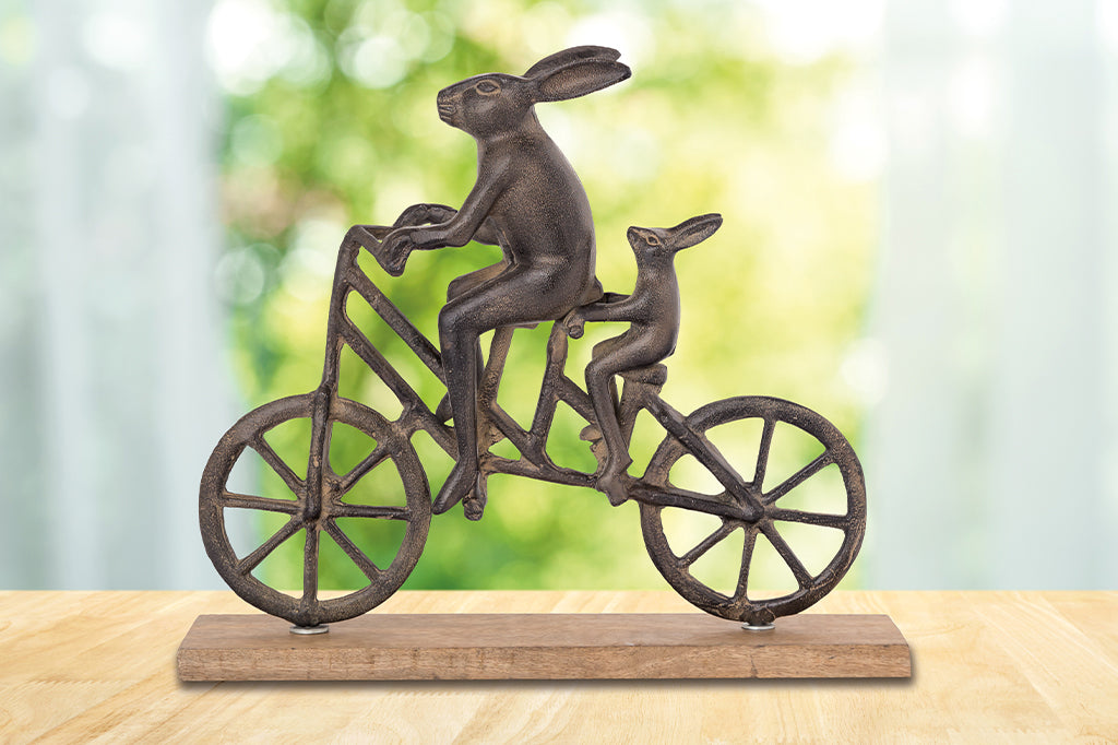 cast metal sculpture, two bunnies riding a tandem bike with wooden base