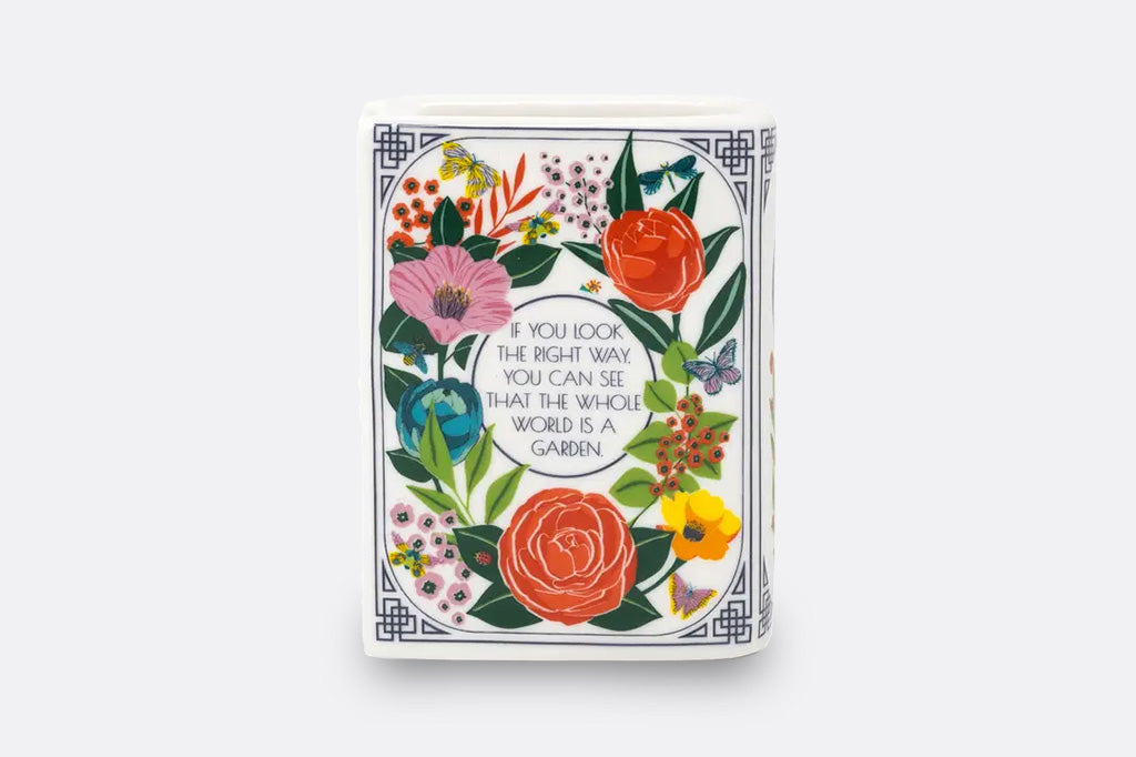 A ceramic and wax candle shaped like a book with flower decorations.