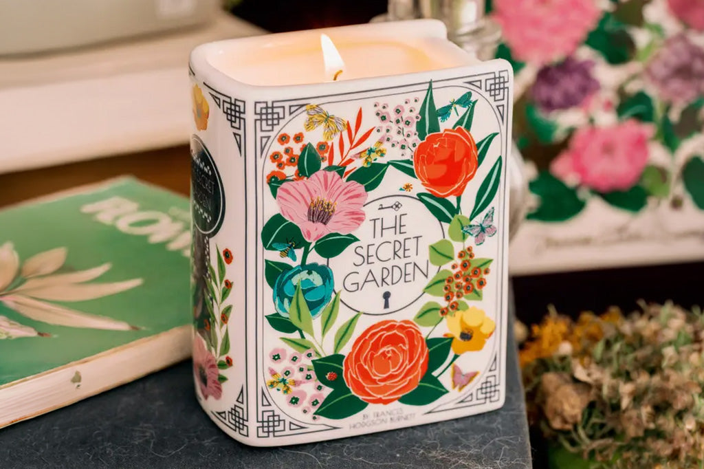 A ceramic and wax candle shaped like a book with flower decorations.