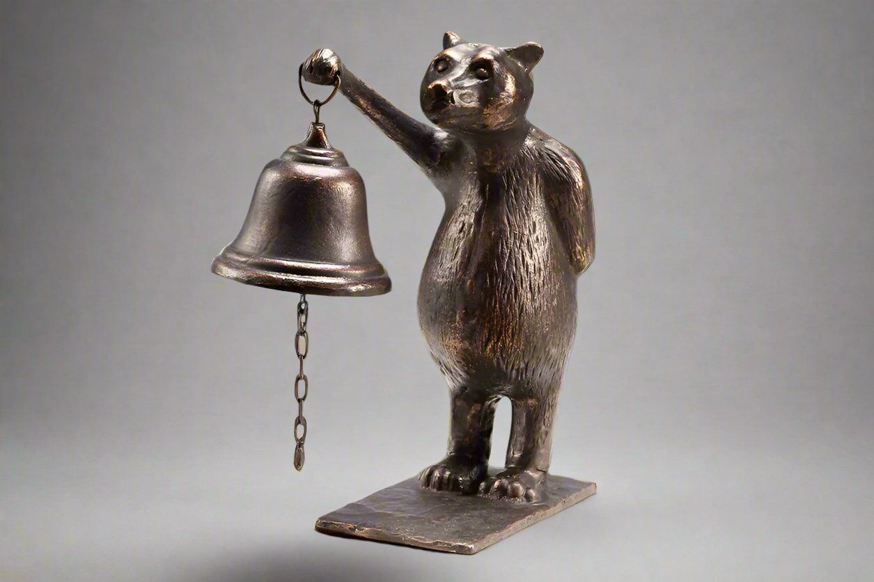 Cast iron brown bear standing on hind legs holding bell on white background