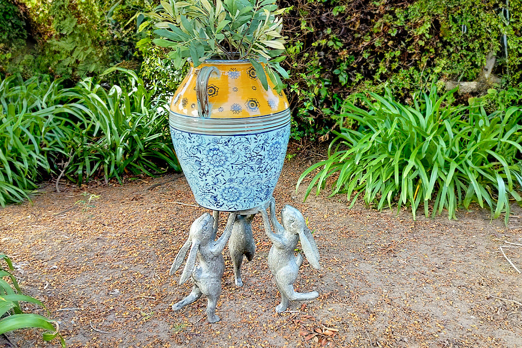 3 bunnies dancing plant stand holding up a mediterranean pot in a shade garden