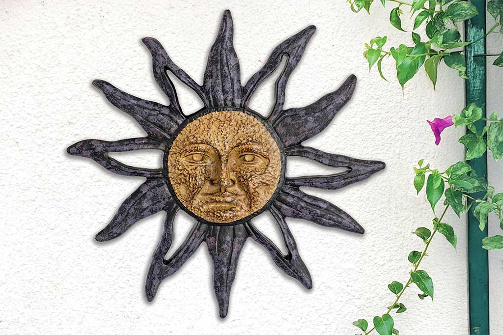 sun with face in center cast metal wall plaque set on outdoor wall