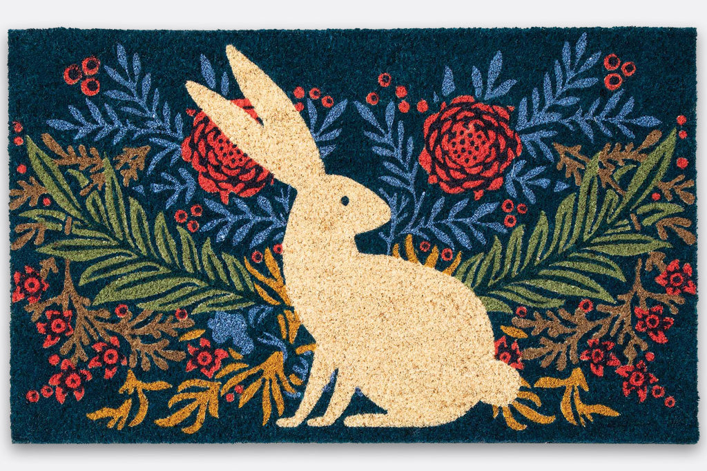 A coir doormat of a bunny on a centered on a floral design.