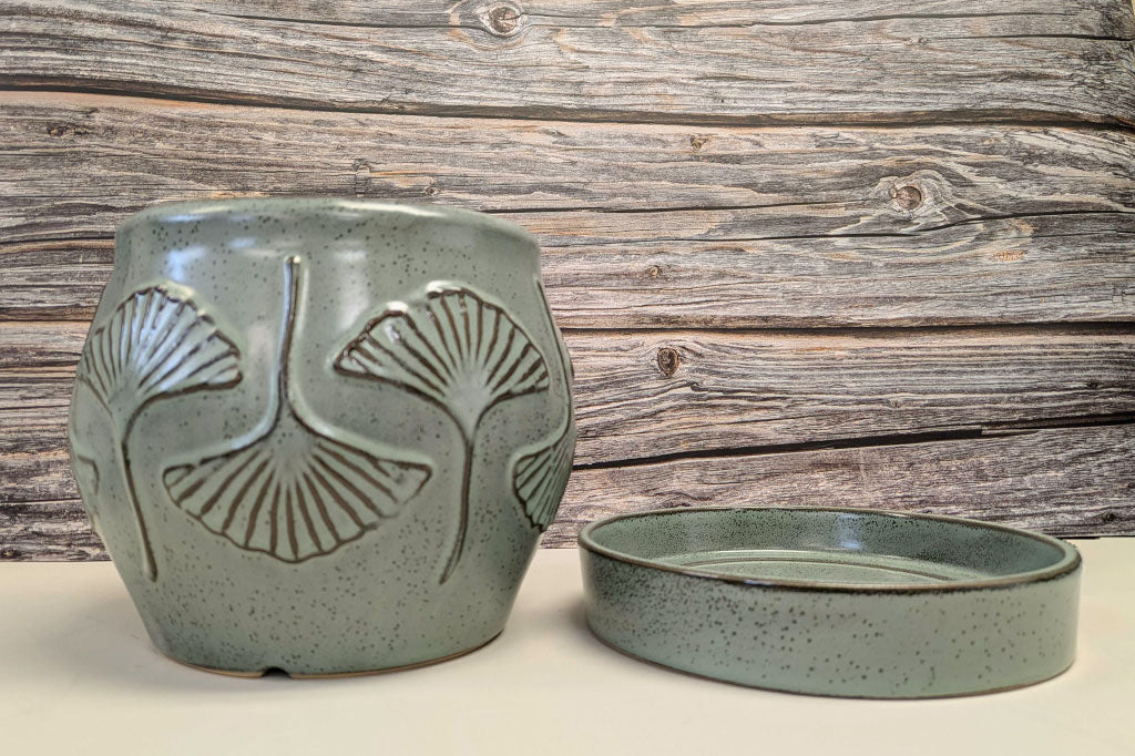Green-grey speckled ceramic planter with ginkgo leaf relief motif shown by its detached saucer