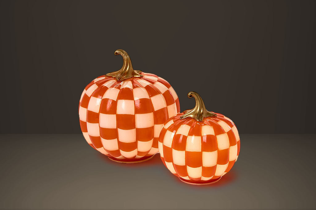 Two checkered glass pumpkins on a dark background, soft glow from internal LED lights
