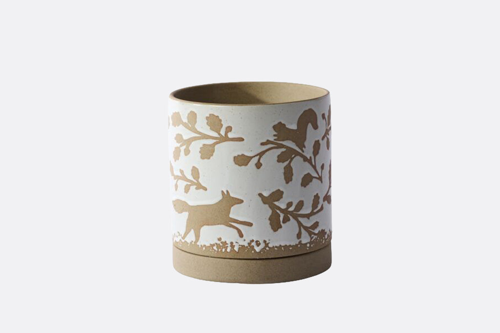 A cylindrical ceramic planter with a white exterior decorated with a brown silhouette pattern of a fox and leafy branches, featuring a solid brown base and matching brown interior.
