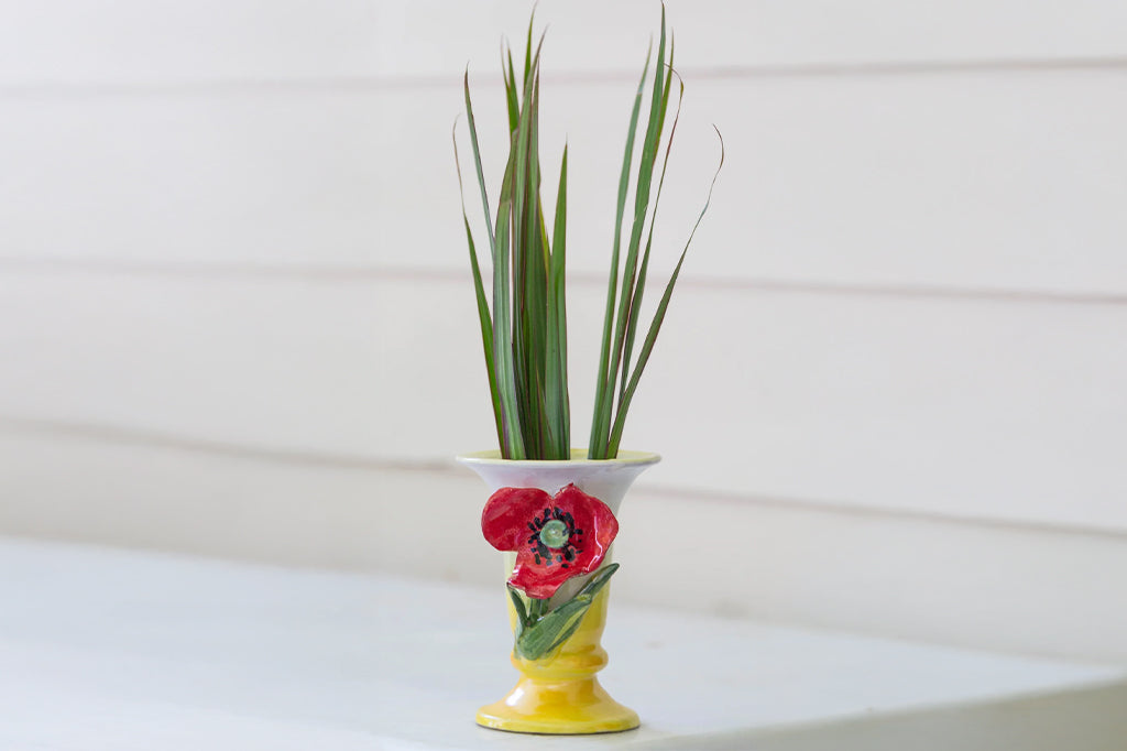 ceramic vase with accent red poppy on front with ornamental grass inside vessel. color of vase Ombre yellow to cream