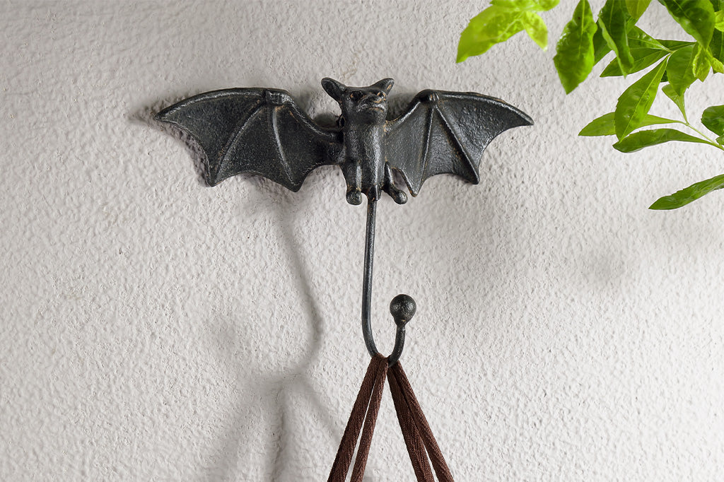 closeup view of bat shaped wall hooks of cast iron shown on wall holding a tote bag