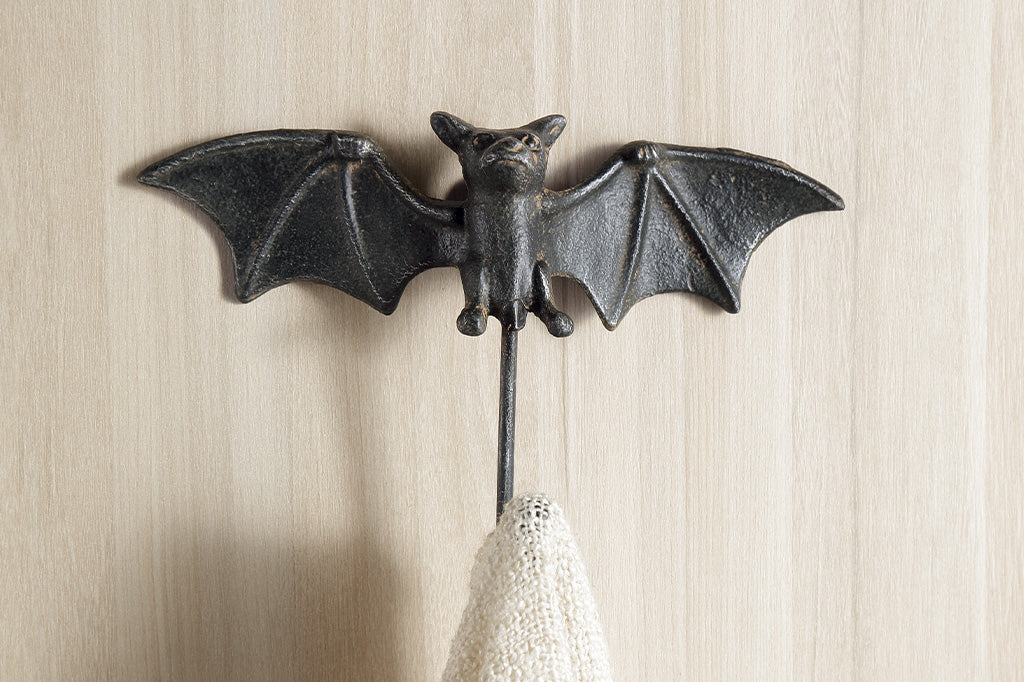 a bat shaped wall hook of cast iron shown on wall holding a scarf