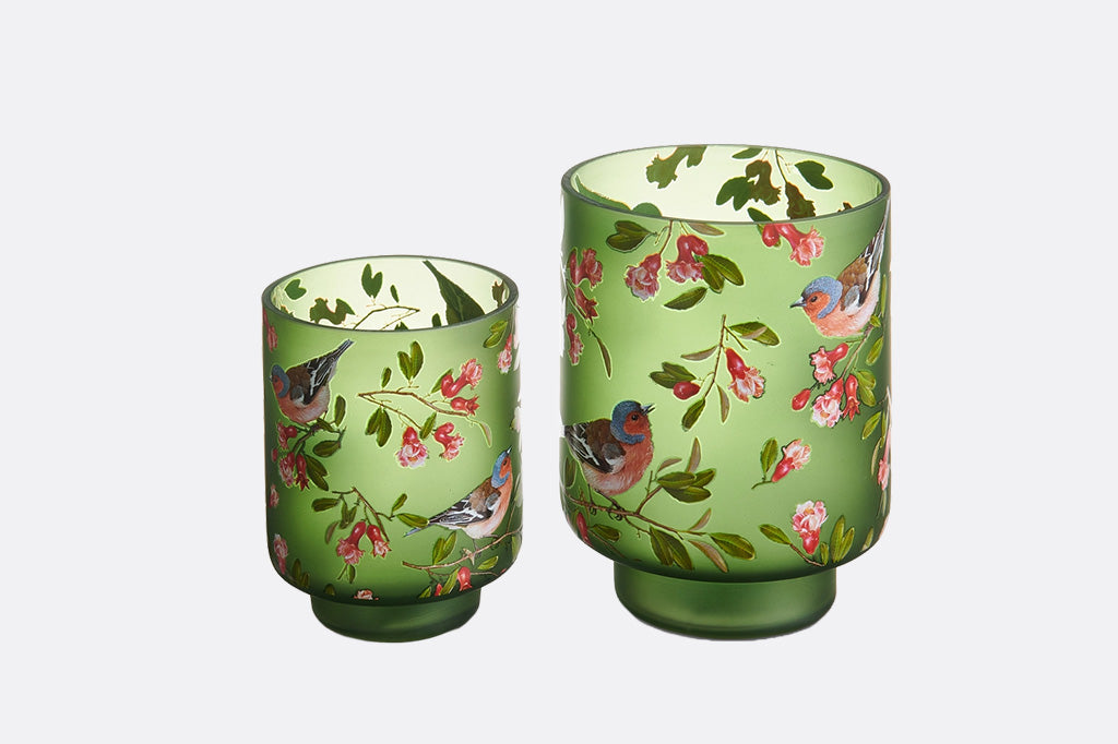 Two green candle holders with floral and bird design on a white background