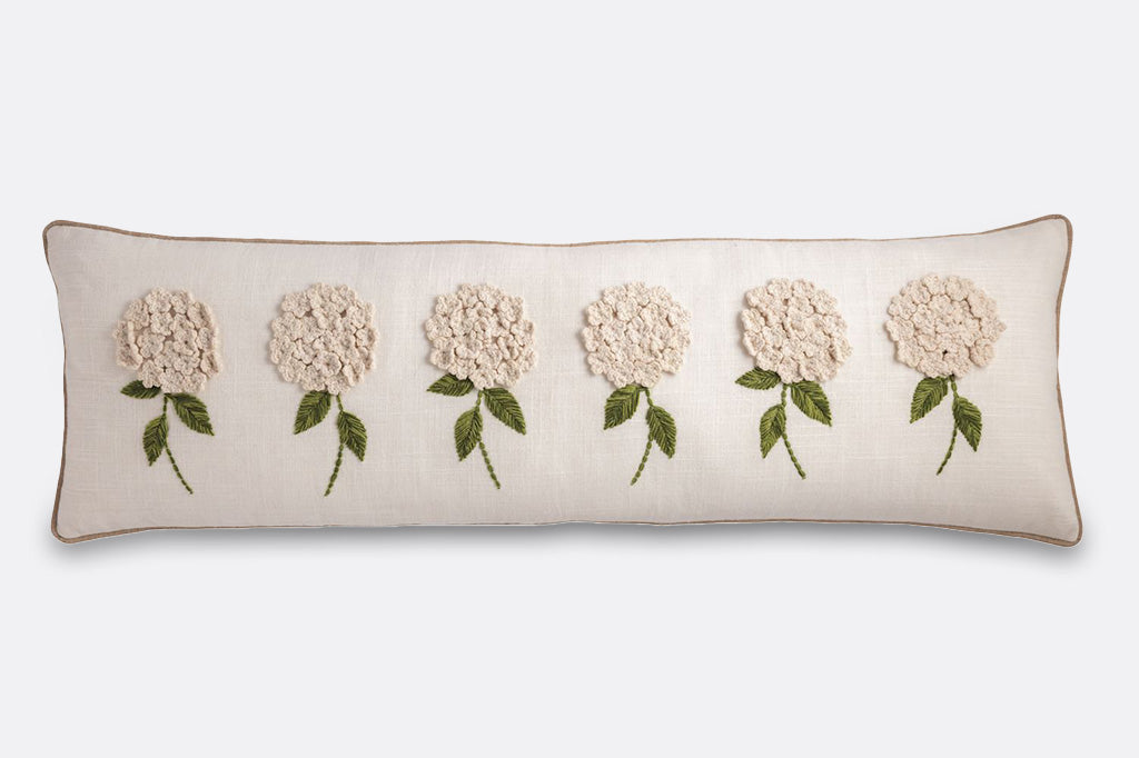 Decorative pillow with embroidered and crocheted flowers on a white background