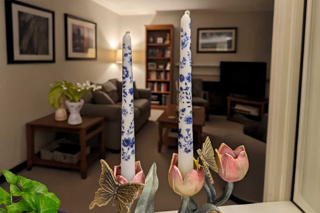 Decorative candles with floral design on a stand in a living room setting.
