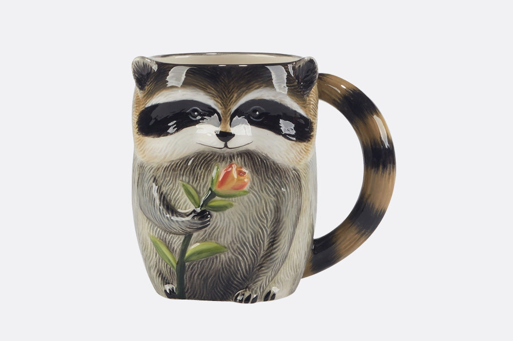 Mug with raccoon design holding a flower on a white background