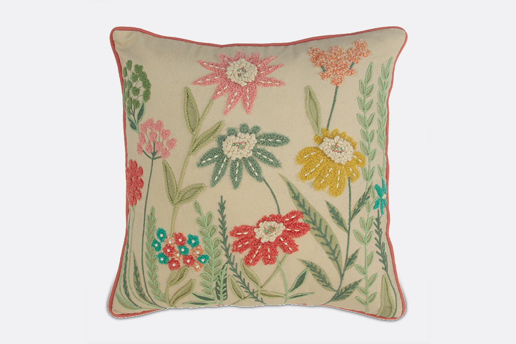 An embroidered pillow with several colorful flowers on it.