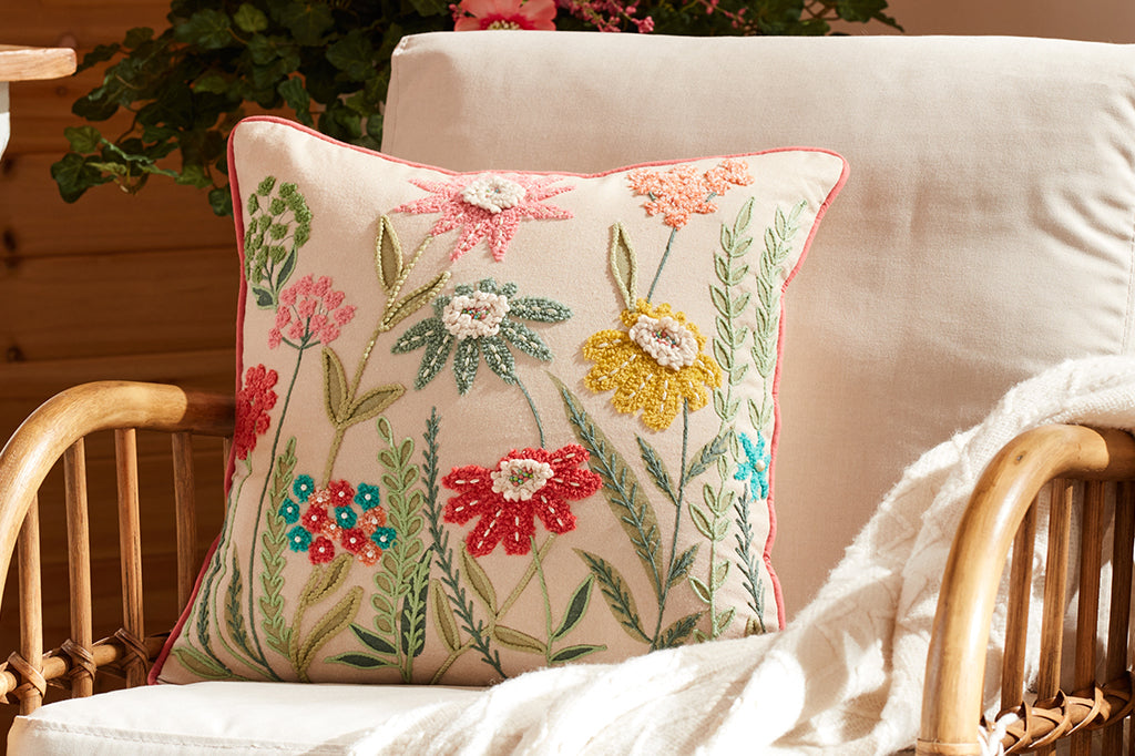 An embroidered pillow with several colorful flowers on it.