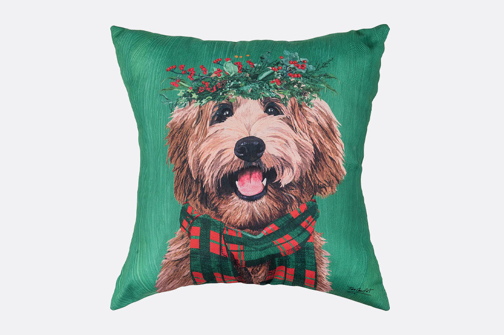 green pillow with labradoodle wearing a green and red plaid scarf and a christmas wreath crown