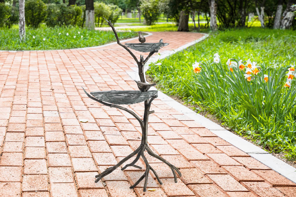 two tier bird feeder/planter shown in a garden on brick path