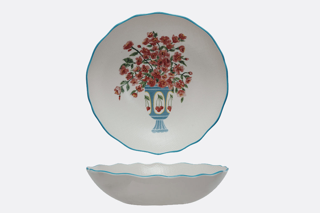 Stoneware bowl with scalloped edges painted in blue with floral arrangement in cheery vase