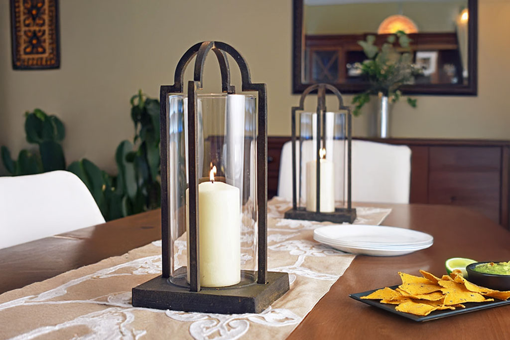 Decorative lanterns with candles on a dining table with plates and chips.