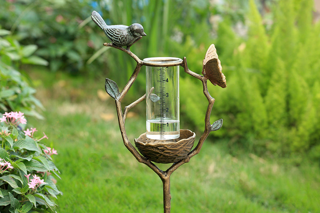 a staked rain catcher in a decorative holder shaped like a nest on a branch, adorned with bird and butterfly